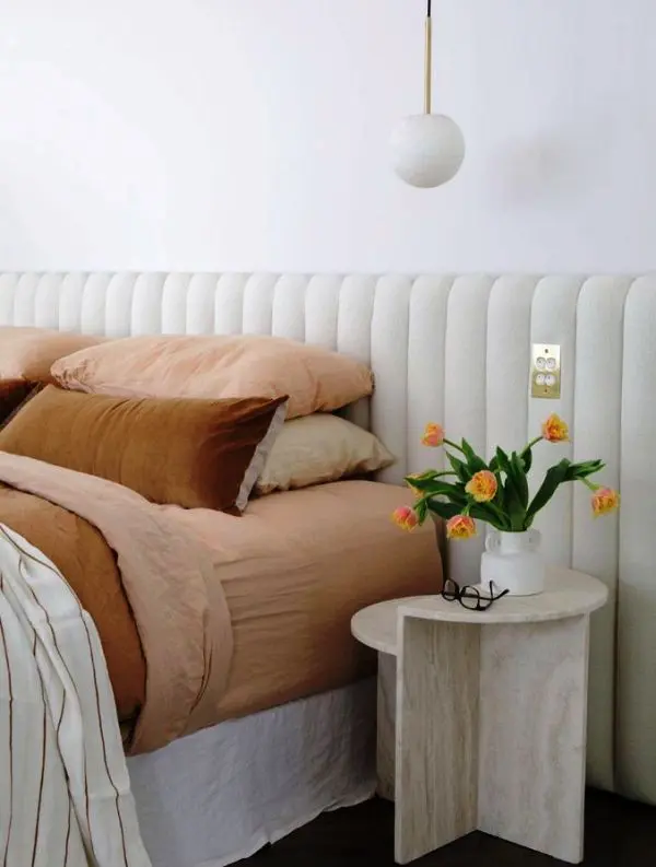 The neutral space is made softer with a ribbed upholstered headboard that brings a trendy feel to the room.