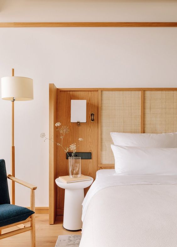 The chic modern bedroom is done with a cool wingback headboard with linen panels, stained wood, lights.